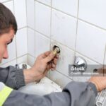 Plumber fixing pipeline  with tool in hands, and checking leaking