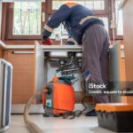 Plumber Unclogging A Kitchen Sink Drain With Pipe Cleaning Machine